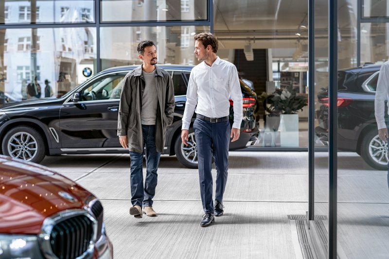 Uitmuntende Service bij uw fleet overeenkomst. 2 personen in businesscontext lopen door een BMW Shrowroom. Op de achtergrond is een BMW X5 te zien.